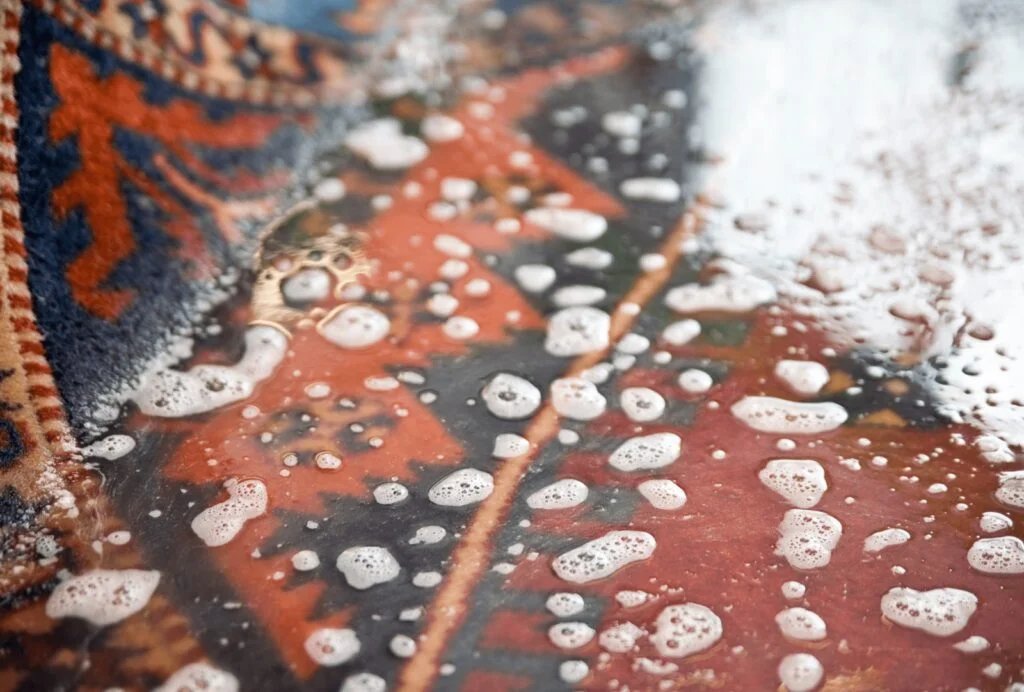 Nettoyage de tapis traditionnel avec brosse et savon.