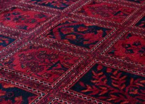 Tapis rouge à motifs géométriques et floraux.