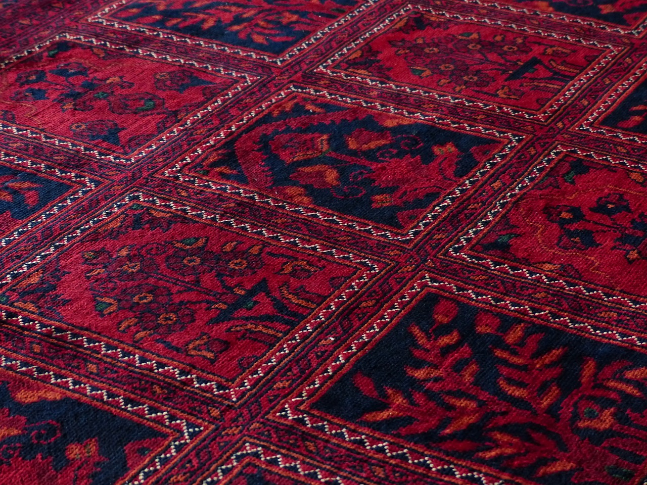 Tapis rouge à motifs géométriques et floraux.